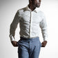 Tankefuld afroamerikansk mand i en hvid skjorte og mønstrede blå bukser, poserer mod en hvid indstilling