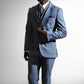 Elegant mand i en grå skræddersyet jakkesæk med et mønstret slips, stirrer eftertænksomt mod en lys baggrund