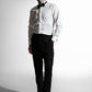 Mand i en klassisk hvid skjorte med sort butterfly, matchet med sorte bukser, der fremviser et formelt look mod en lys indstilling