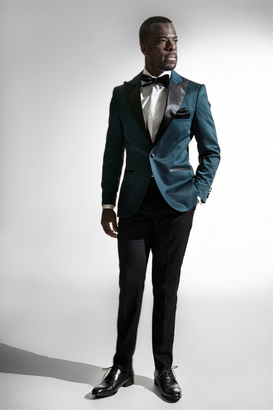 Stilfuld mand i en teal farvet blazer med en matchende butterfly, sat mod en lys baggrund