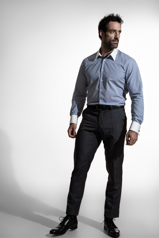 Stilfuld mand i en stribet blå skjorte og stribede bukser, der betragter tankefuldt til siden